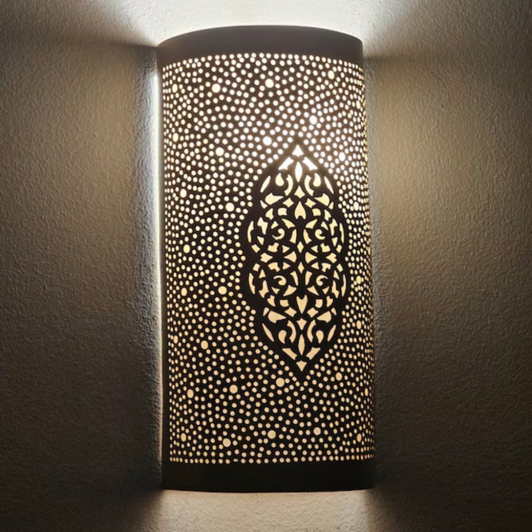 Detailed shadow play of a perforated Moroccan brass lamp projecting artistic patterns on a dark wall.