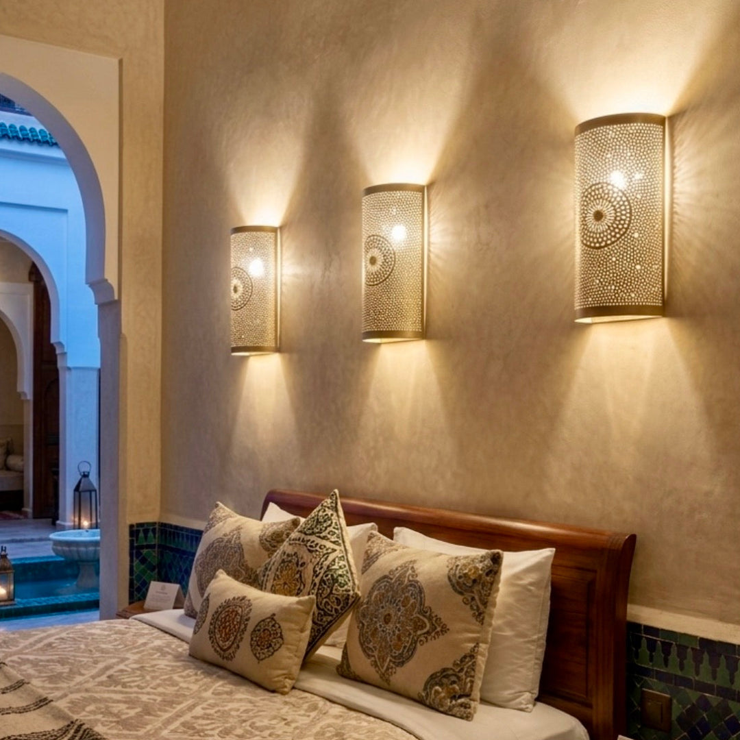  Elegant Moroccan brass sconces mounted above a bed in a luxury suite, blending traditional craftsmanship with European hotel decor styles.