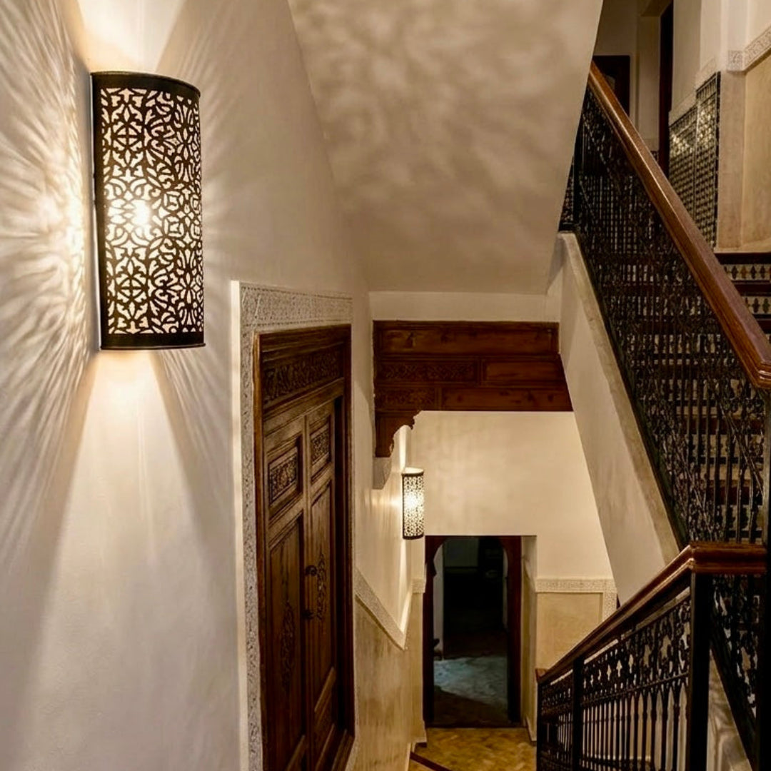 Hand-crafted brass wall lighting illuminating a traditional Moroccan staircase with a warm glow.