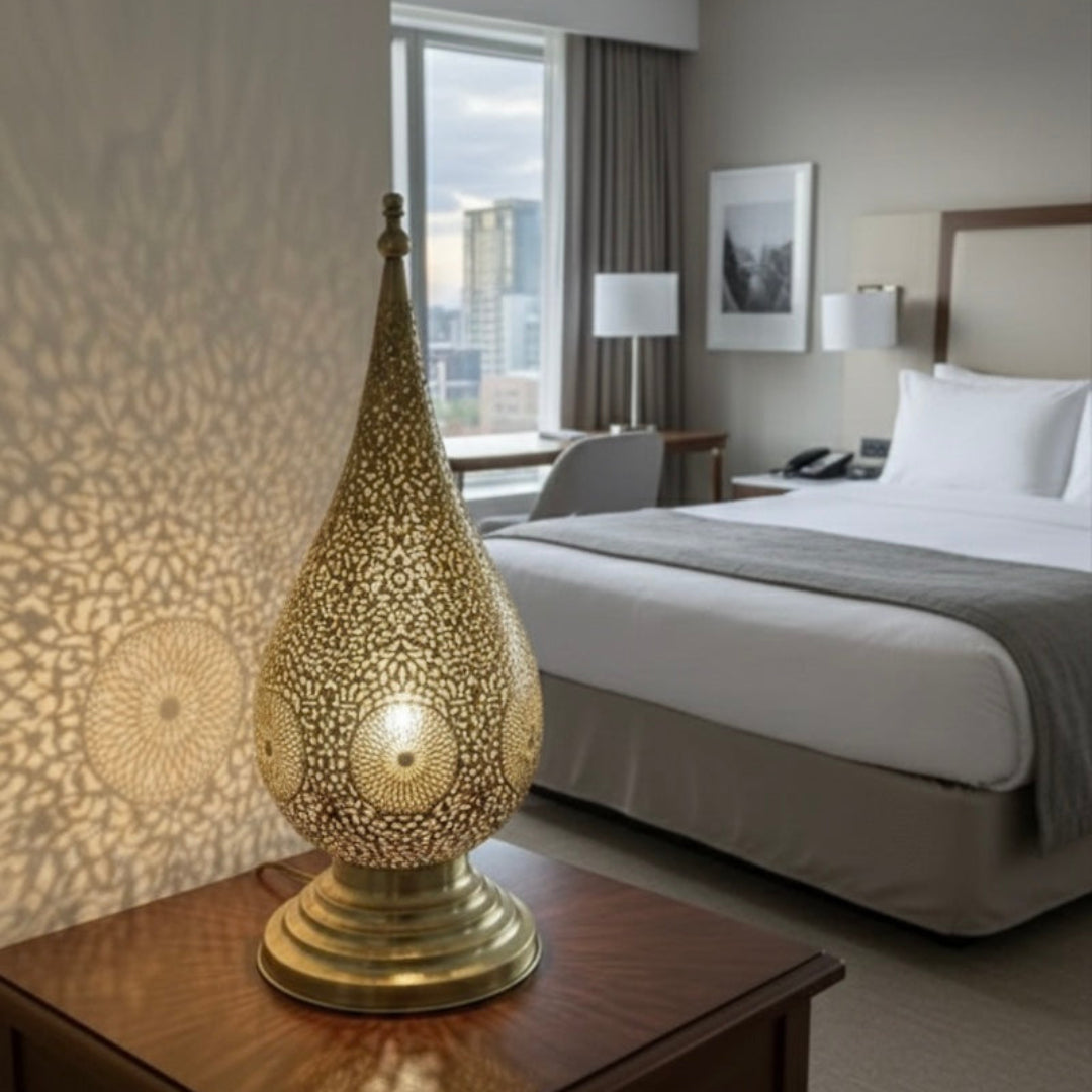 Elegant Moroccan brass teardrop lamp on a wooden nightstand in a bright, modern hotel suite