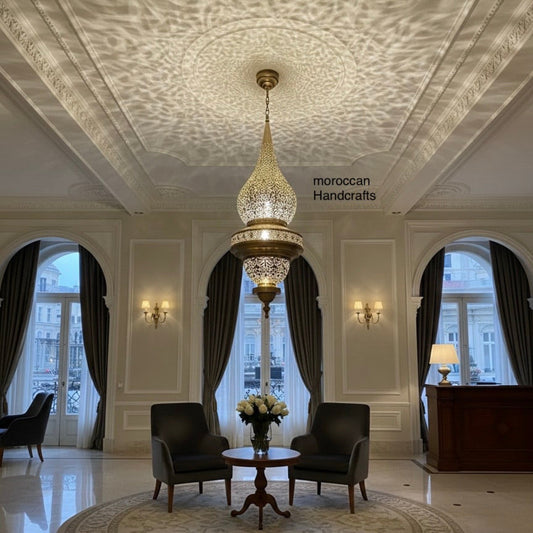 Handcrafted Moroccan teardrop brass pendant light, illuminated and casting an intricate shadow pattern on the ceiling.