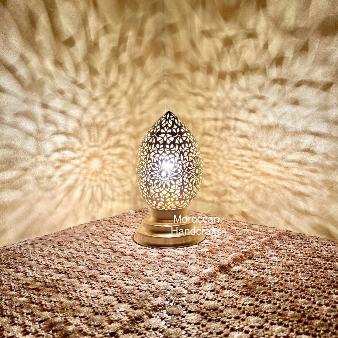 Handcrafted Moroccan egg-shaped lamp casting intricate star-like geometric shadow patterns on the wall.