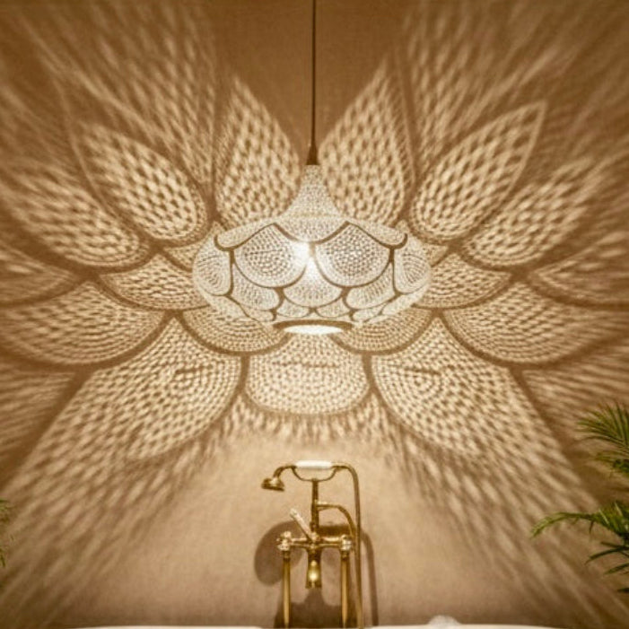 Traditional Moroccan brass lamp reflected in a luxury bathroom with a golden bathtub and exotic plants.