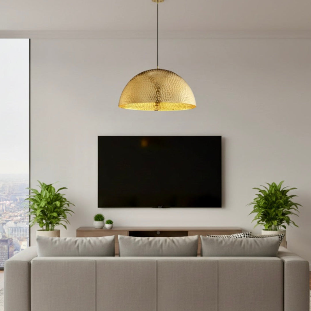 Oversized gold hammered brass dome light hanging in a contemporary living room above a sofa and TV unit.