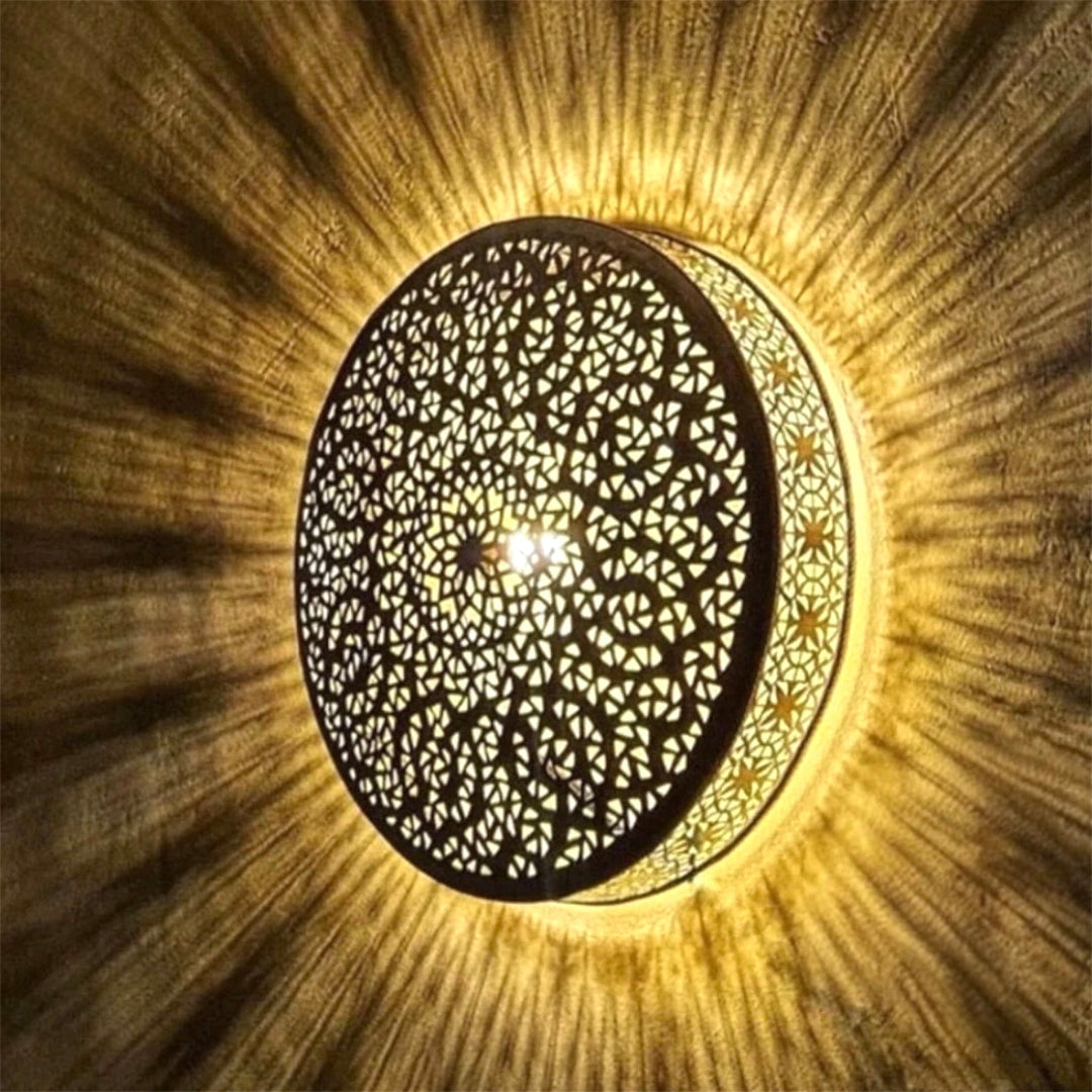 ⁠Symmetrical overhead view of a handmade pierced brass lamp illuminated, showcasing traditional Arabesque and geometric light designs.⁠