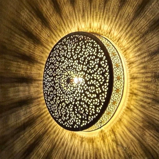 ⁠Symmetrical overhead view of a handmade pierced brass lamp illuminated, showcasing traditional Arabesque and geometric light designs.⁠