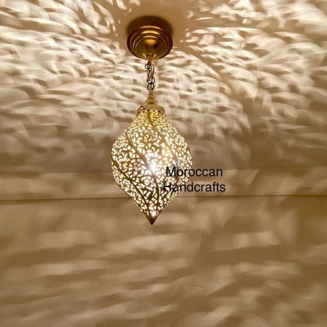 Handcrafted Moroccan brass pendant light in a tear drop shape, featuring an intricate leaf pattern that casts dramatic shadows.