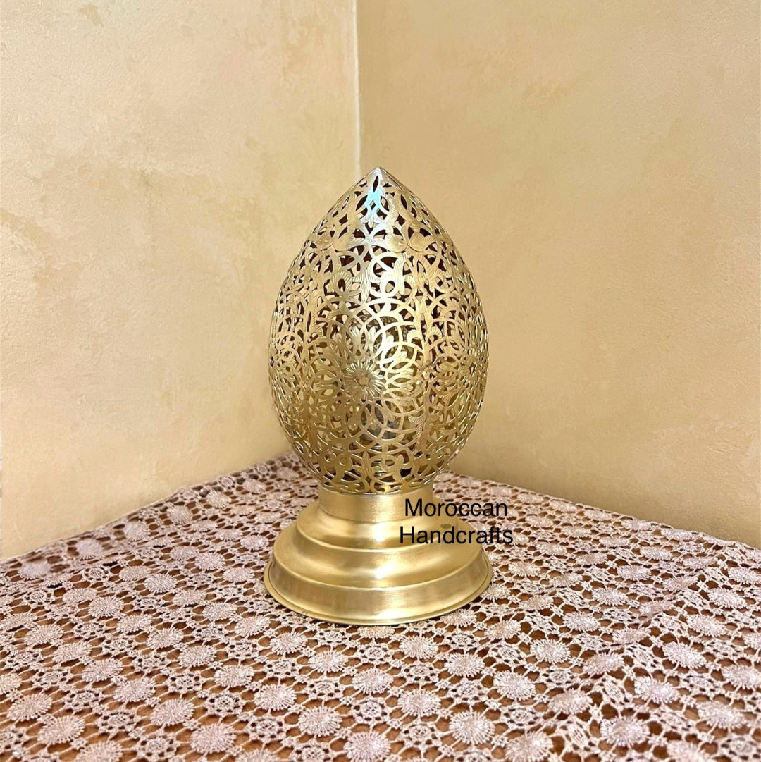 Close-up of a small brass teardrop-shaped lamp with delicate filigree metalwork for accent lighting.