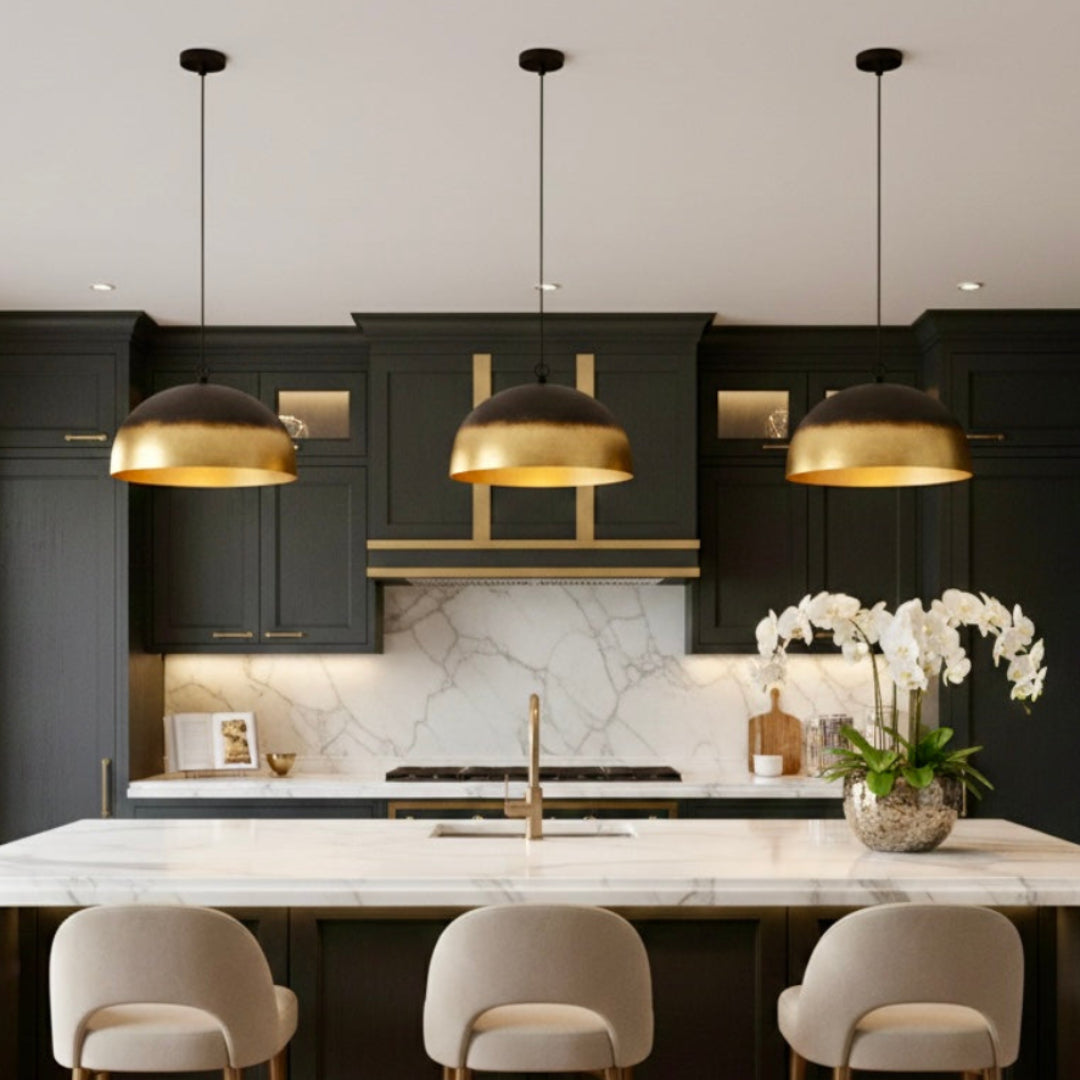  Three Moroccan handmade brass dome lamps hanging over a luxury black and marble kitchen island.