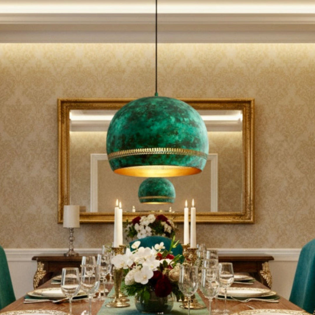 Moroccan artisan-made patina green pendant lamp over a classic wooden dining table with teal chairs.