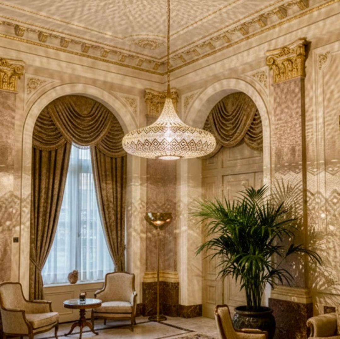 Elegant vintage lounge with high ceilings and a large Moroccan brass chandelier creating shadow art on classical architecture.